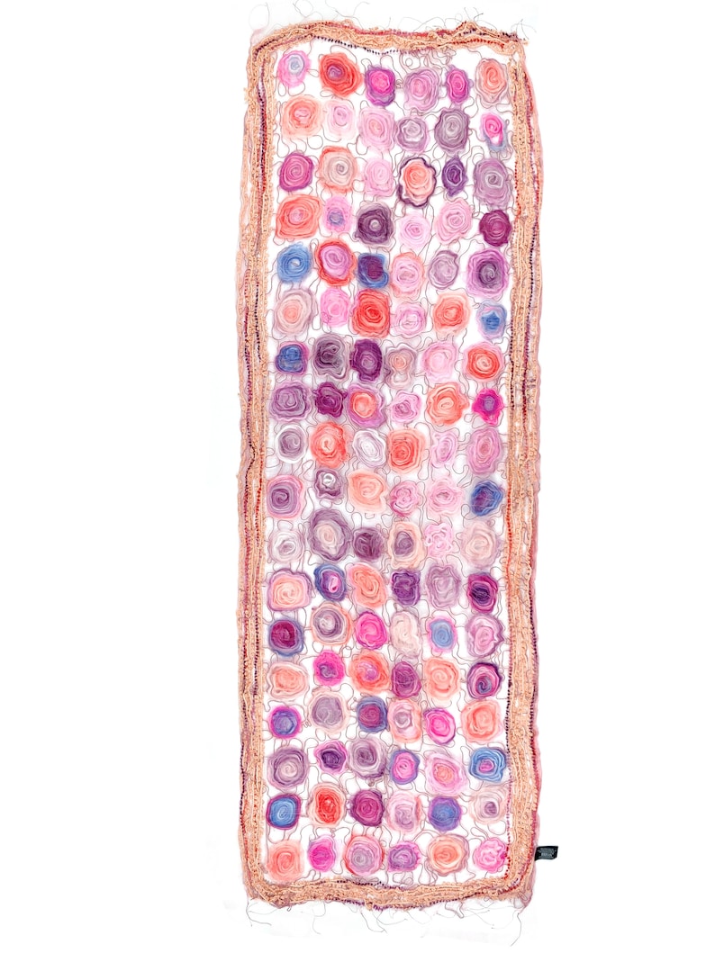 May include: A rectangular scarf featuring a pattern of colorful, spiral-shaped floral designs in shades of pink, purple, and orange. The scarf has a crocheted border in a light brown color and a small black tag.