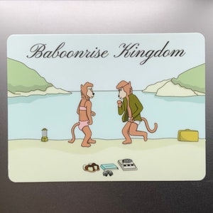 Op de afbeelding: Een sticker met een cartoonillustratie van twee bavianen op een strand. De tekst "Baboonrise Kingdom" staat bovenaan de sticker.