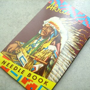 Puede incluir: Una portada de libro vintage con un hombre nativo americano con un tocado de plumas de colores. La portada es amarilla, roja y azul con el texto "Akron Needle Book".