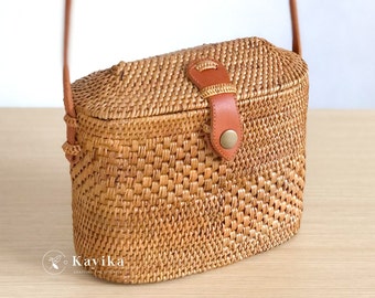 May include: A woven brown crossbody bag with a leather flap and a brass buckle closure. The bag has a long brown strap.