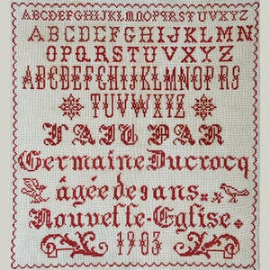 Könnte beinhalten: Ein weißer Stoff-Sampler mit roten gestickten Buchstaben, Zahlen und einem floralen Muster. Der Sampler enthält das Alphabet, Zahlen und den Text "FAIT PAR Germaine Ducrocq agée de 9 ans Nouvelle-Eglise 1903".