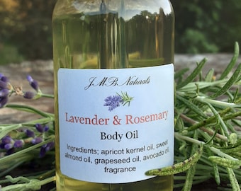 May include: A clear glass bottle with a black dropper top filled with a light yellow liquid. The bottle has a white label with the text "JMB Naturals Lavender & Rosemary Body Oil" and a list of ingredients.