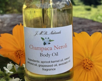 May include: A glass bottle of Champaca Neroli Body Oil by J.M.B. Naturals. The bottle is clear and has a textured surface. The label is white with black text and a small floral design. The ingredients are listed on the label: apricot kernel oil, sweet almond oil, grapeseed oil, avocado oil, and fragrance.