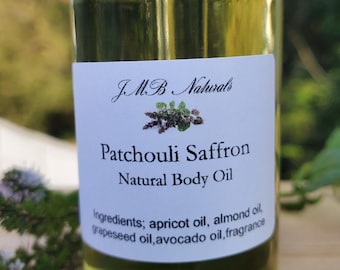 May include: A clear glass bottle of J.M.B. Naturals Patchouli Saffron Natural Body Oil. The label lists ingredients: apricot oil, almond oil, grapeseed oil, avocado oil, and fragrance. The bottle is filled with a yellow liquid.