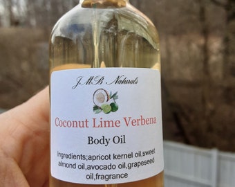 May include: A clear glass bottle with a black dropper top and a white label. The label reads "JMB Naturals Coconut Lime Verbena Body Oil" and lists the ingredients: apricot kernel oil, sweet almond oil, avocado oil, grapeseed oil, and fragrance.