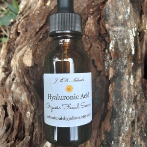 May include: A brown glass bottle with a black dropper top. The bottle is labeled "J.M.B. Naturals Hyaluronic Acid Organic Facial Serum jmbnaturalsbyjuliana.etsy.com"