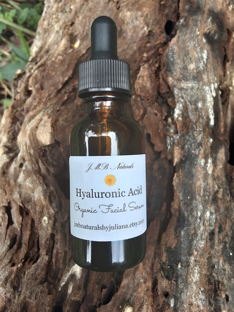 May include: A brown glass bottle with a black dropper top. The bottle is labeled "J.M.B. Naturals Hyaluronic Acid Organic Facial Serum jmbnaturalsbyjuliana.etsy.com"