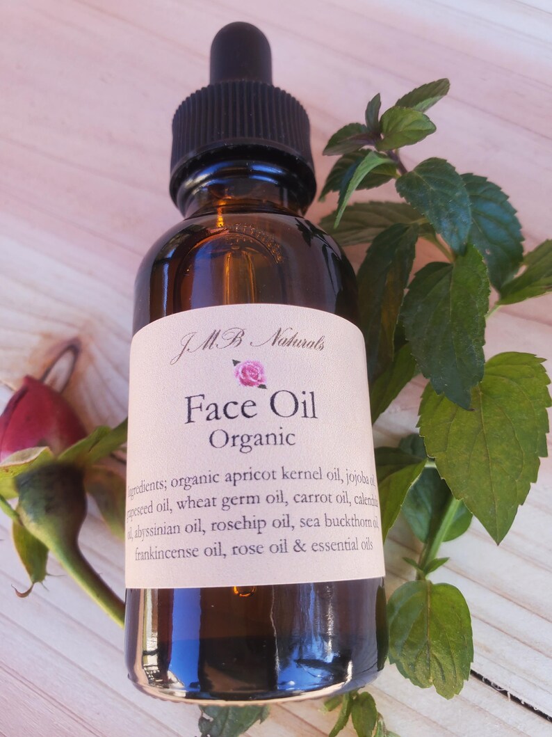 May include: A brown glass bottle with a dropper top and a white label that reads "JMB Naturals Face Oil Organic". The label lists the ingredients: organic apricot kernel oil, jojoba seed oil, wheat germ oil, carrot oil, calendula oil, Abyssinian oil, rosehip oil, sea buckthorn oil, frankincense oil, rose oil & essential oils.
