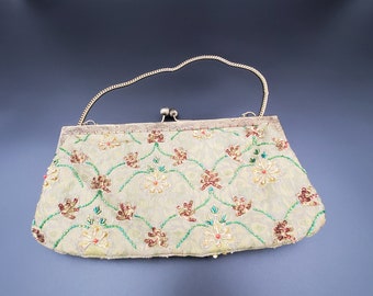 May include: A light green beaded evening bag with a floral design. The bag has a gold chain strap and a clasp closure.