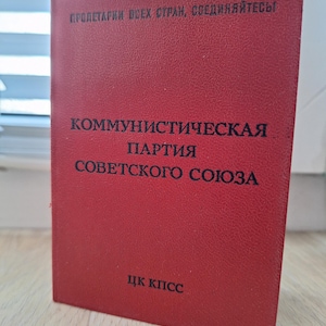 May include: A red book with the text "ПРОЛЕТАРИИ ВСЕХ СТРАН, СОЕДИНЯЙТЕСЬ!" at the top and "КОММУНИСТИЧЕСКАЯ ПАРТИЯ СОВЕТСКОГО СОЮЗА" in the middle. The bottom of the book has the text "ЦК КПСС".