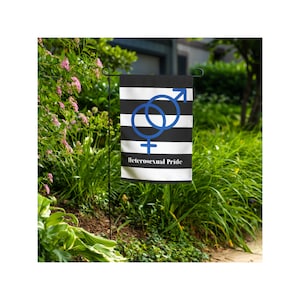 Puede incluir: Una bandera de jardín con rayas horizontales negras y blancas. La bandera presenta un símbolo masculino y femenino azul entrelazado y las palabras "Heterosexual Pride" en texto blanco.