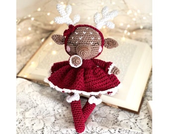 May include: A crocheted reindeer toy wearing a red dress with white trim. The reindeer has brown yarn for its body and white yarn for its antlers.