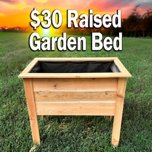 May include: A rectangular raised garden bed constructed from light brown wood with a visible grain pattern. The interior is lined with a black fabric material. The text $30 Raised Garden Bed is displayed in large white letters above the planter.