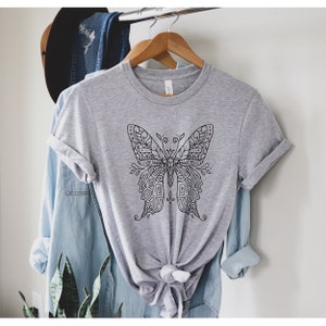 May include: A gray t-shirt with a black and white intricate butterfly design.