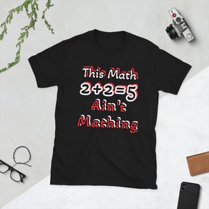 Może przedstawiać: Czarny T-shirt z białym tekstem, który brzmi "This Math 2+2=5 Ain't Mathing". Tekst jest obwiedziony czerwonym kolorem.