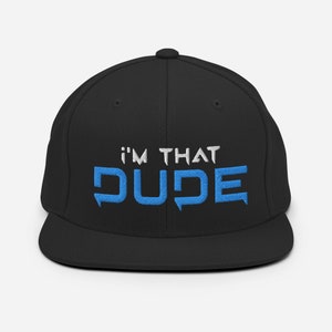 Può includere: Cappellino da baseball nero con testo ricamato in bianco e nero. Il testo recita "I'm That DUDE" con la parola "DUDE" in blu.