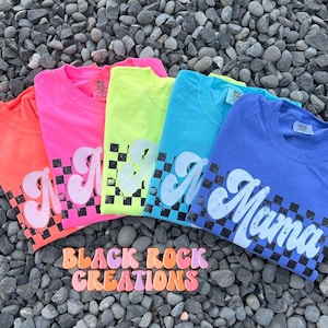 May include: Five neon colored t-shirts with a black and white checkered pattern and the word "Mama" in a retro font.