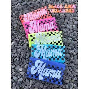 May include: Five colorful t-shirts with a checkered pattern and the word "Mama" printed in white on each shirt.