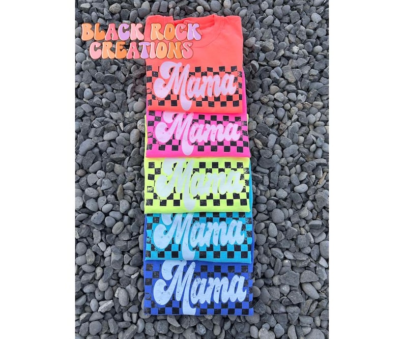 May include: Stack of six t-shirts with a checkered pattern and the word "Mama" in a retro font. The shirts are in various colors, including pink, yellow, blue, and green.
