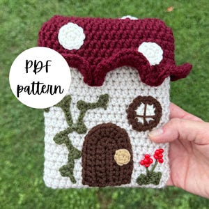 May include: A crocheted house-shaped item with a burgundy mushroom-style roof with white spots. The house has a brown door, a round window, and green vines. The text "PDF pattern" is in a white circle.