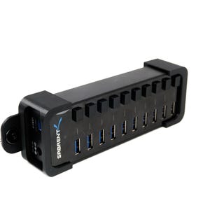 May include: A black USB hub with multiple ports, featuring the brand name "Sabrent" in blue. The hub has a rectangular shape with a series of USB ports and a power input. The design is sleek and modern, suitable for connecting multiple devices.