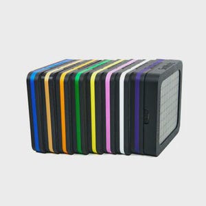 May include: A row of square, black-framed LED light panels arranged side-by-side. Each panel features a distinct coloured border in blue, gold, orange, green, yellow, pink, white, and purple, with a grid-patterned light surface on the front.