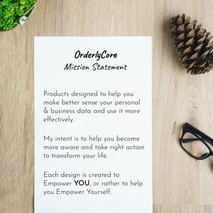 May include: A white sheet of paper with black text on a wooden surface. The text reads "Orderly Core Mission Statement" and includes a mission statement about helping people make better sense of their personal and business data.
