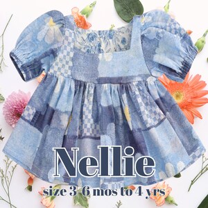 May include: A blue patchwork dress with short, puffed sleeves and a square neckline. The dress features a mix of floral and checkered patterns in shades of blue. The word "Nellie" is displayed in white text, with "size 3-6 mos to 4 yrs" below.