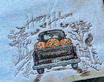May include: A light blue sweatshirt with an embroidered design of a black pickup truck carrying pumpkins and the text "Happy Halloween".