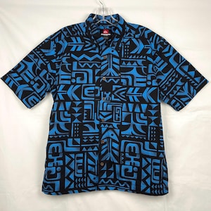 Puede incluir: Una camisa de manga corta con botones, con estampado azul y negro, con el logotipo de Quicksilver en el pecho izquierdo.