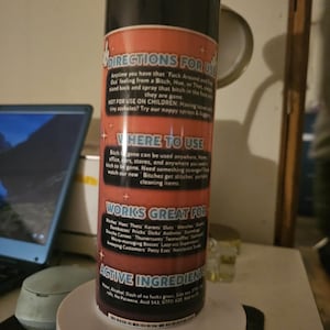 Puede incluir: Una botella de spray negra y roja con texto que dice "DIRECTIONS FOR USE" y "WORKS GREAT FOR". La botella es cil&iacute;ndrica y se asienta sobre una base blanca. El texto es en blanco y rojo.