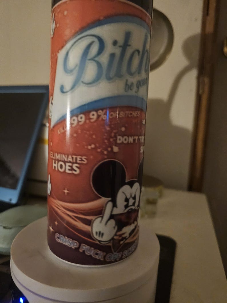 Puede incluir: Un vaso cil&iacute;ndrico con un dise&ntilde;o degradado rojo y marr&oacute;n. El vaso presenta el texto "Bitch be gone" y "Eliminates hoes". Un rat&oacute;n de dibujos animados est&aacute; mostrando el dedo medio. Tambi&eacute;n es visible el texto "Crisp fuck off scum".
