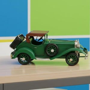 May include: A green vintage toy car with a brown convertible roof and black luggage. The car has black wheels and is on a light-coloured table. The background is a colourful grid pattern.