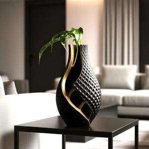 May include: A black vase with a gold accent design and a diamond pattern. The vase is on a black table and contains a green plant. The vase has a modern design and is in a living room setting.