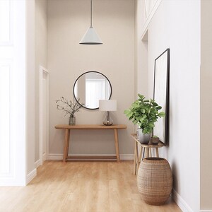 May include: A well-lit hallway with light wood flooring and neutral-colored walls. A round mirror hangs above a wooden console table. A pendant light hangs from the ceiling. A woven basket and potted plants add decorative elements.