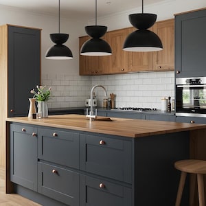 May include: A modern kitchen with a large island featuring a wooden countertop and dark gray cabinets. Black pendant lights hang above the island. The kitchen also has wooden cabinets and white tile backsplash.