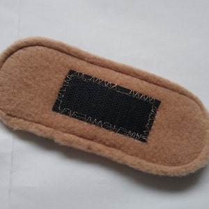 May include: A brown fleece fabric rectangle with a black velcro patch sewn in the center.