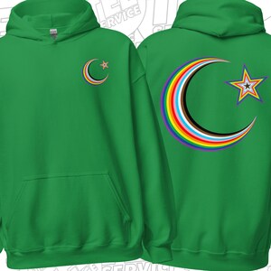 Puede incluir: Sudadera con capucha verde con un diseño de luna creciente y estrella arcoíris. La parte delantera presenta una pequeña luna creciente con un arcoíris y una estrella. La parte trasera muestra una versión más grande del mismo diseño. La sudadera tiene un bolsillo delantero y una capucha.