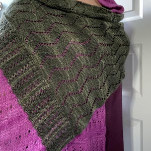 May include: A green and purple knitted shawl with a lacy pattern. The shawl is draped over a person's shoulders.