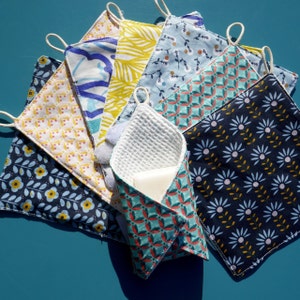 Peut inclure: Un ensemble de carrés de tissu colorés avec différents motifs, notamment floraux, géométriques et abstraits. Les carrés sont disposés en pile, avec un carré de tissu blanc en nid d'abeille sur le dessus. Les carrés de tissu sont probablement destinés à être utilisés comme chiffons ou serviettes réutilisables.