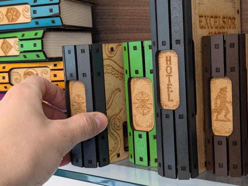 May include: A set of five wooden game pieces with different colored backgrounds and designs. The pieces are labeled "Hotel", "Excelsior Hotel", and have a star and an octopus design.