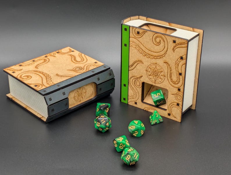 May include: Two wooden book-shaped dice towers with a tentacle design. The towers are open on the top and have a small slot for dice to fall through. Green dice are scattered around the towers.