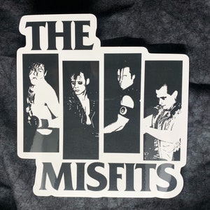 May include: Black and white sticker featuring a band logo with the text "THE MISFITS" and four band members in silhouette.