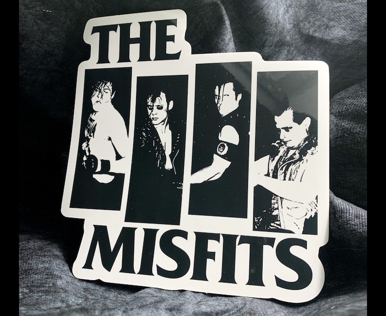May include: Black and white sticker featuring the band The Misfits. The sticker has a black and white image of the band members with the band name in white letters.