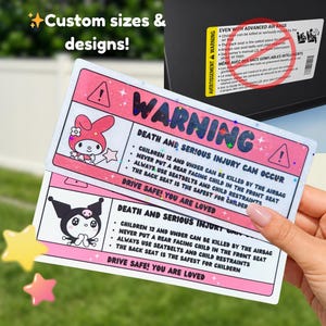 May include: Pink and white warning stickers with cartoon characters and safety information. The stickers warn about the dangers of airbags for children and advise on safe car seat practices. Text includes "Death and Serious Injury Can Occur".