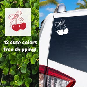 May include: A white car window decal featuring a pair of red heart-shaped cherries tied with a bow. The text "12 cute colors" is visible in the image.