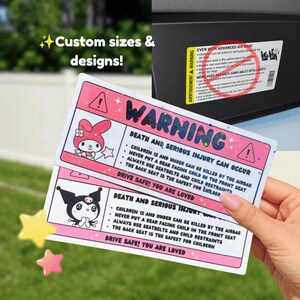 May include: Two pink and white warning stickers with cartoon characters and safety information. The stickers read "WARNING" and provide safety instructions regarding children and airbags. The text "Custom sizes & designs!" is also visible.