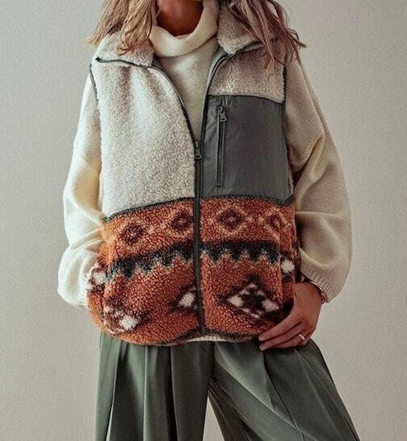 May include: A cream, brown, and green fleece vest with a zipper closure and a geometric pattern. The vest has a large pocket on the front.