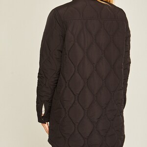 May include: A black quilted long-sleeve shirt with a button-up front and a curved hem.