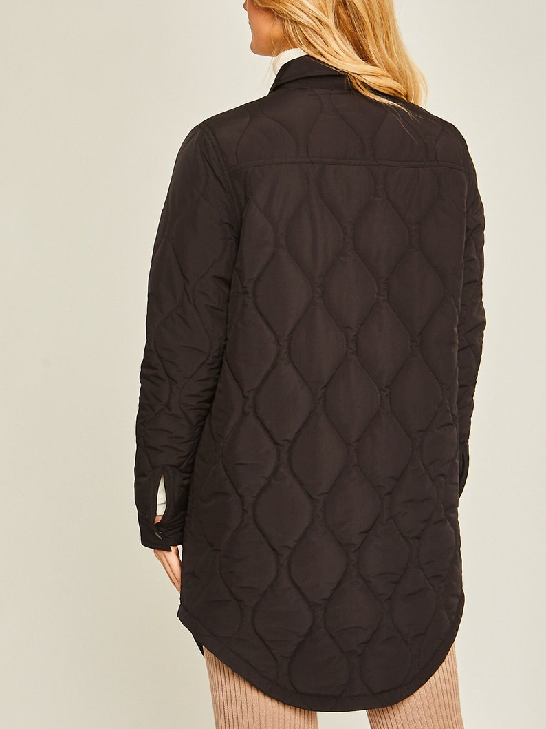 May include: A black quilted long-sleeve shirt with a button-up front and a curved hem.